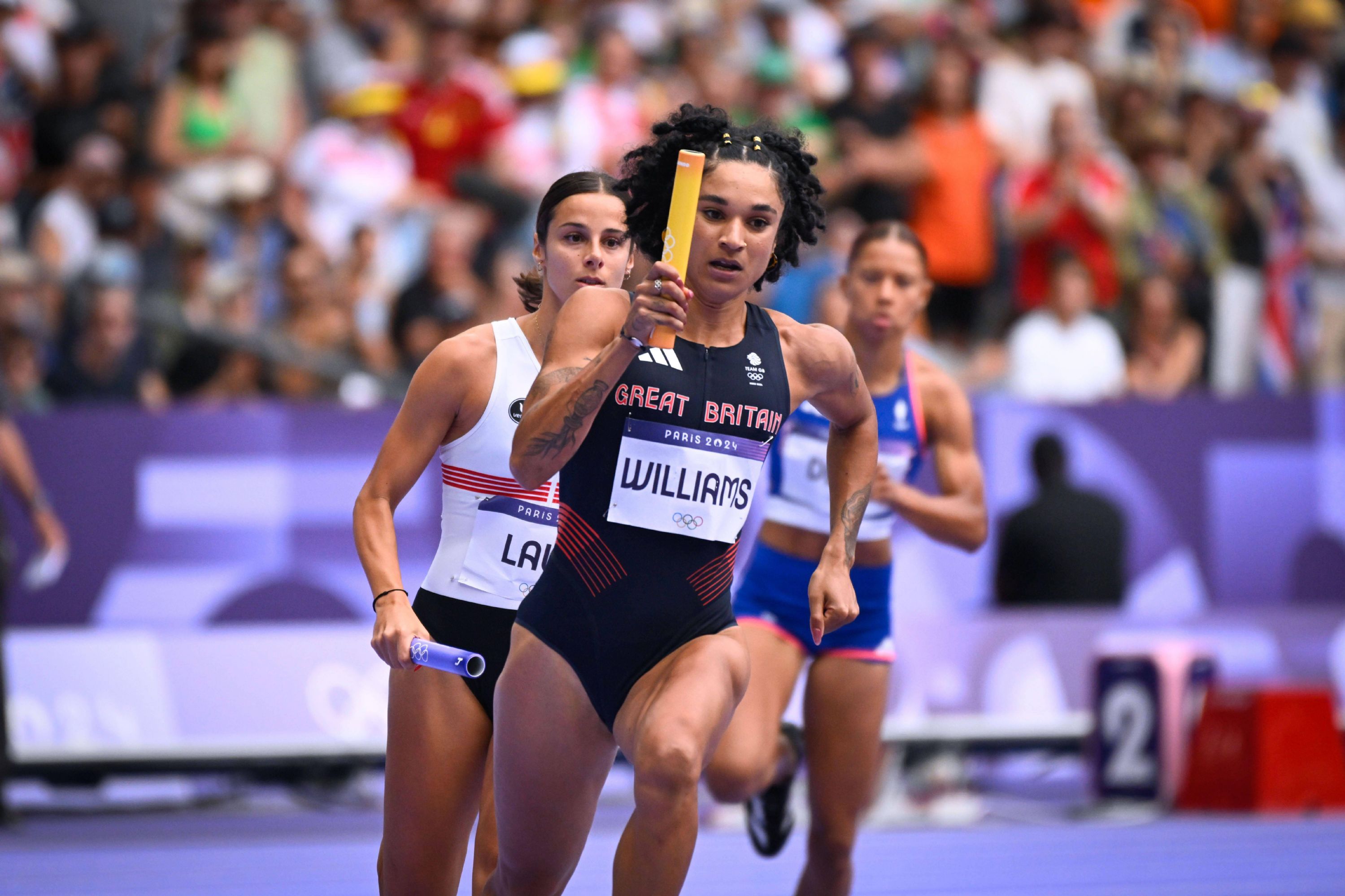 Jodie Williams races with her baton in a heat of the women's 4x400m at the Paris Olympics