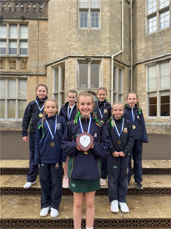 netballers hold their winning shield on the steps outside Canford school in Dorset