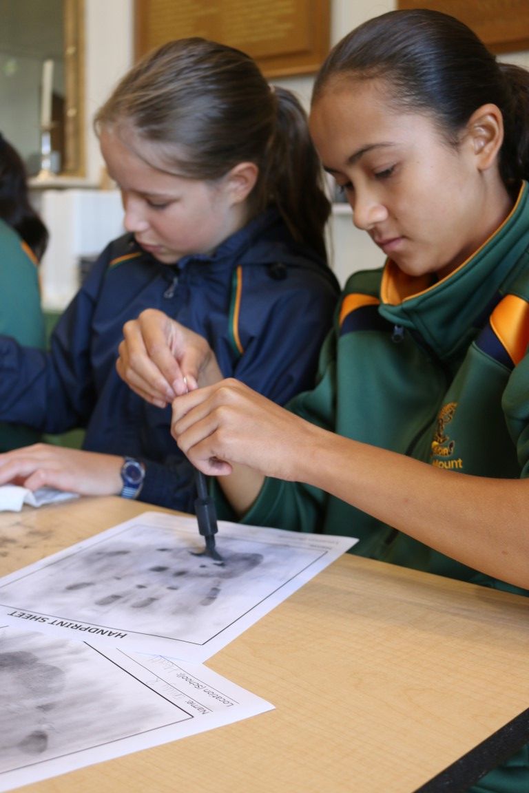 A girl uses iron filings to reveal fingerprints during a forensic science workshop