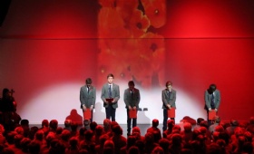 Boys stand with bowed heads in front of a backdrop of poppies as they read names of Heath Mount pupils who lost their lives in the world wars