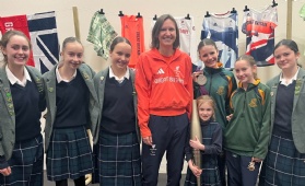 Verity Naylor poses with students holding a London 2012 Paralympic Silver Medal and a Paris 2024 Paralympic Torch